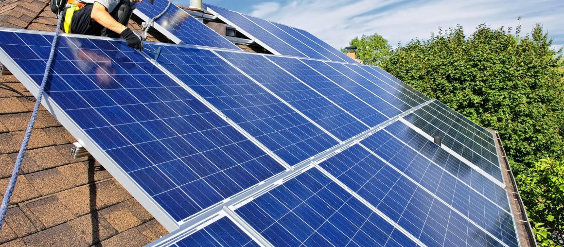 Человек устанавливает фотоэлектрические солнечные батареи альтернативной энергии на крыше